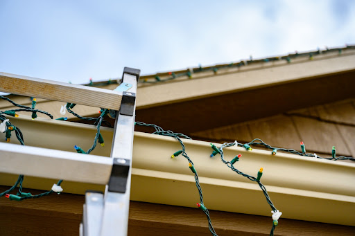 a ladder on a roof where Christmas lights have been hung